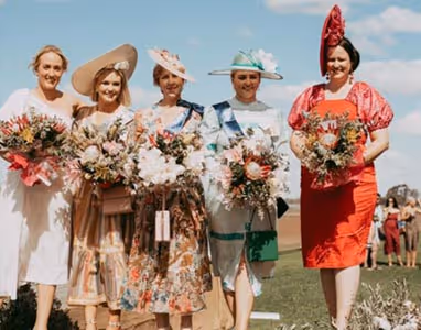 Image of 5 ladies dressed up holding bouquets of flowers.